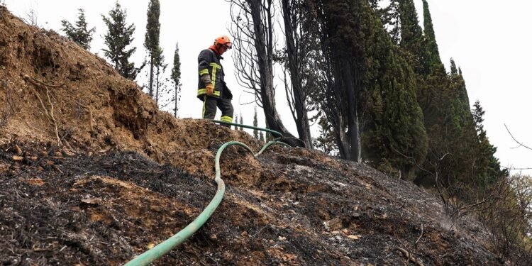 A firefighter works to prevent a wildfire from reigniting, in Fontjoncouse, southern France, August 6, 2025. REUTERS/Manon Cruz